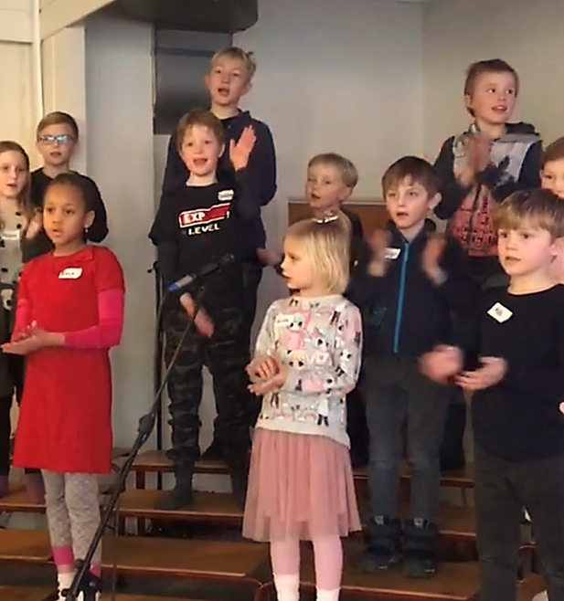 Barn i alderen 5-11 år som står på en scene og synger