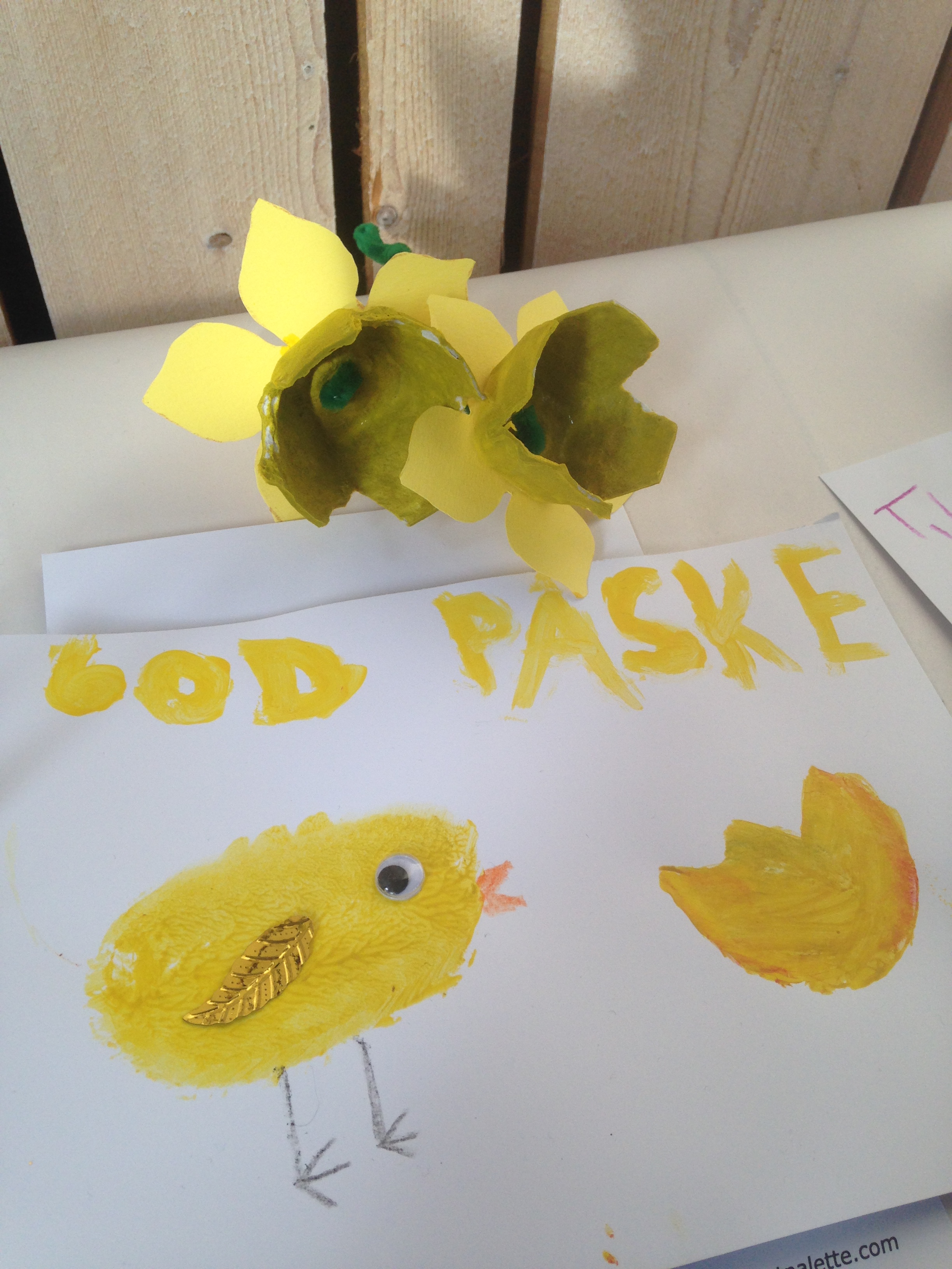 Foto av en gul påskelilje laget av eggekartong og papir, og et ark med en malt påskekylling med overskrift 