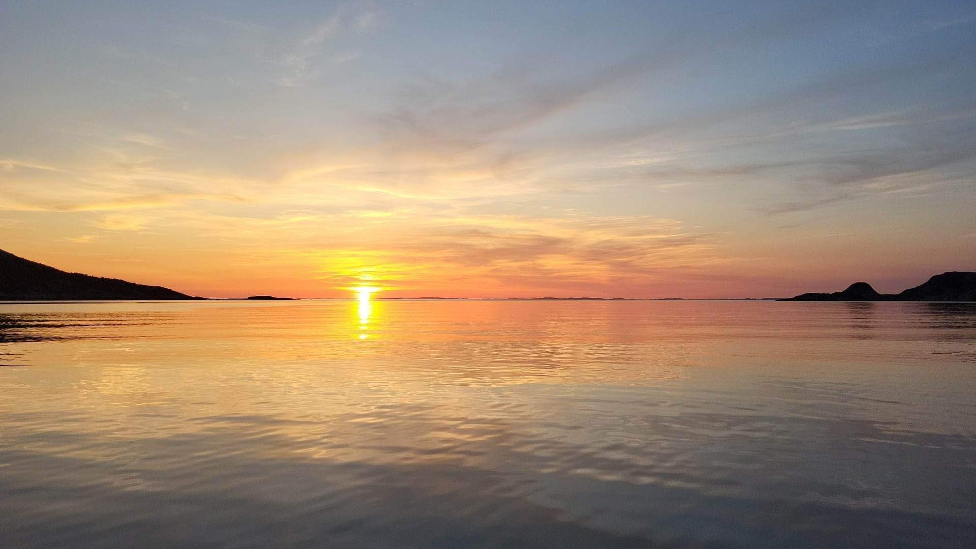 Sol i horisonten mellom himmel og hav.